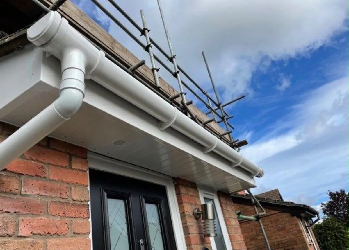 White fascia, soffit and gutter fitted beneath scaffolding
