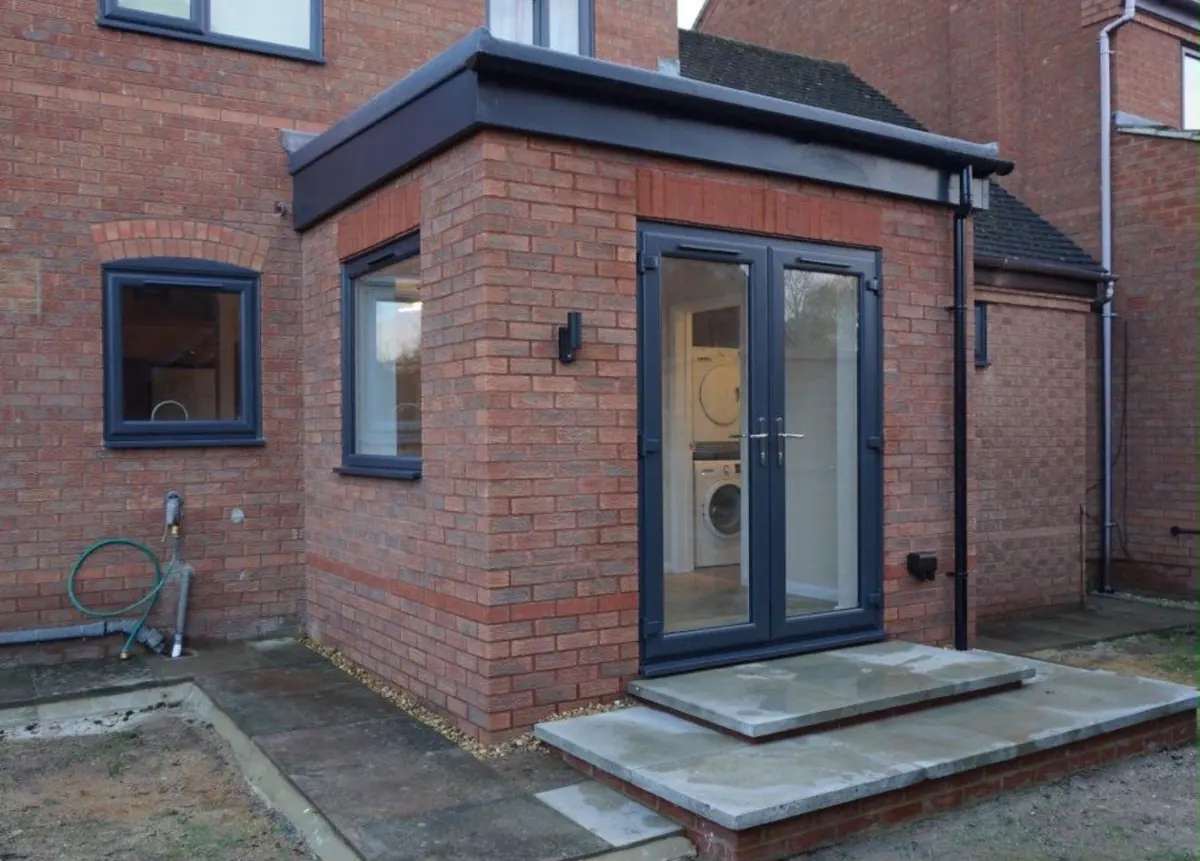 Brick extension with a grey flat roof and French doors