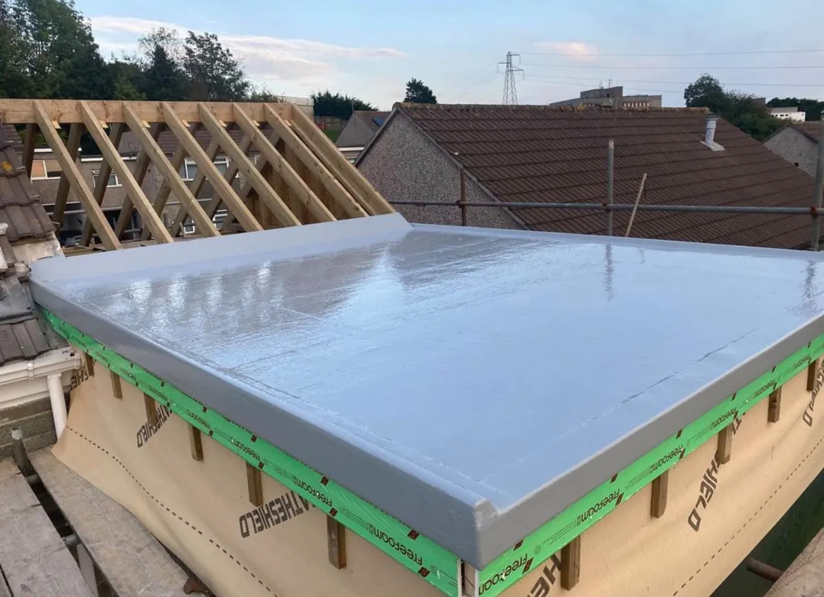 Grey GRP fibreglass flat roof beside new timber rafters