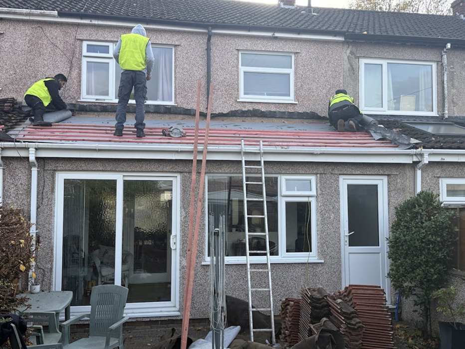 Three Yellowstone roofers in hi-vis re-roofing a rear lean-to roof
