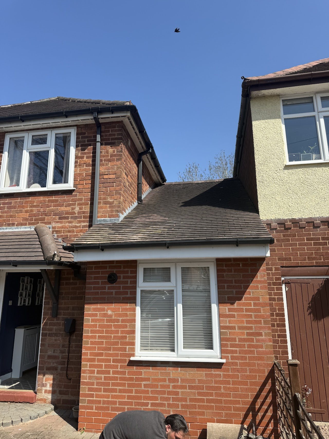Roofer working on the porch roof of a brick house