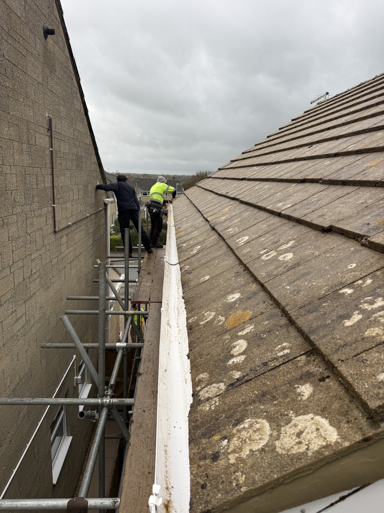 Roofers working along the gutter line from scaffolding